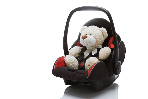 Toy bear in car seat for kids isolated on white background.