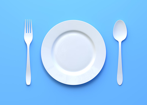 Close-up shot of dinner plate with cutlery isolated on white background.