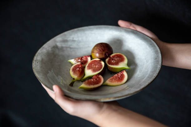 Holding a plate of cut figs, vegan food.