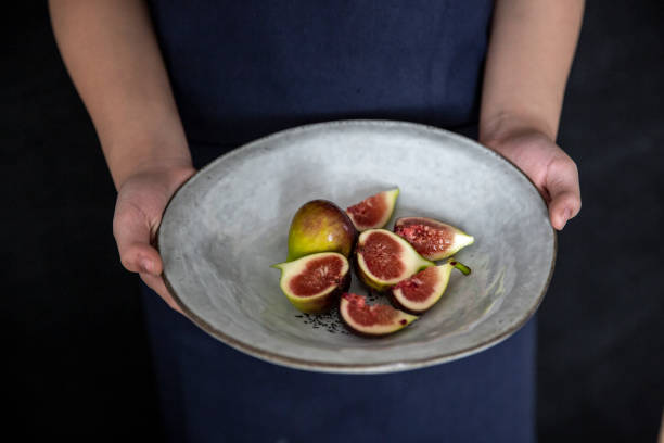 Holding a plate of cut figs, vegan food.