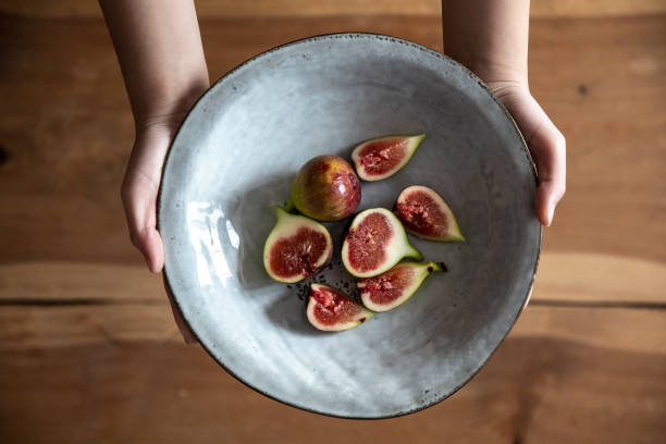 Holding a plate of cut figs, vegan food.