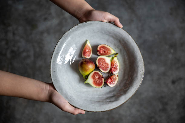 Holding a plate of cut figs, vegan food.