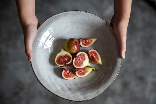 Holding a plate of cut organic figs, vegan food.