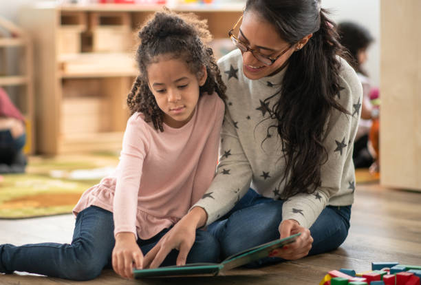 istock Teacher and student read a book together 1402880643