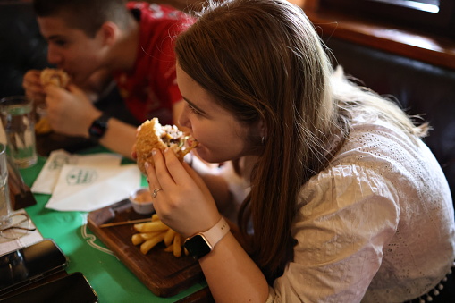 Brother and sister eating burgers together in a restaurant
