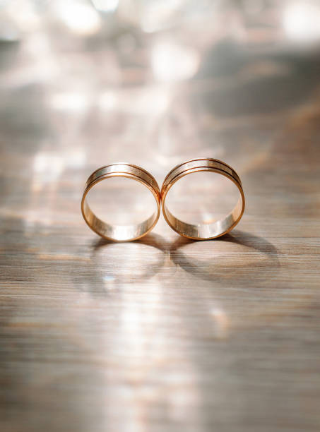 anéis de casamento dourados com bokeh brilhante na superfície de madeira, conceito de amor eterno. closeup - couple gold pair vertical - fotografias e filmes do acervo