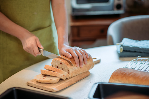 crop shot of women hands cutting freshly made bread