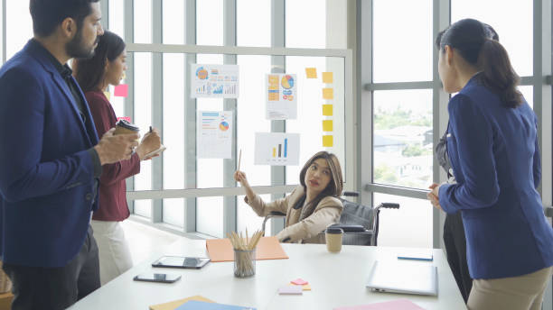 istock Disabled people with a group of Asian business team talk, communicate, discuss, and work in meeting room office, present ideas to colleagues. People lifestyle. Corporation 1402886067