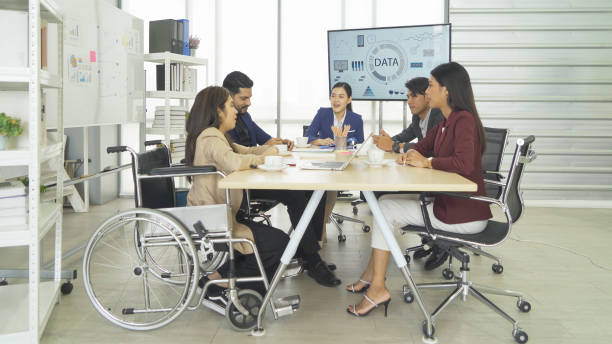 istock Disabled people with a group of Asian business team talk, communicate, discuss, and work in meeting room office, present ideas to colleagues. People lifestyle. Corporation 1402886078