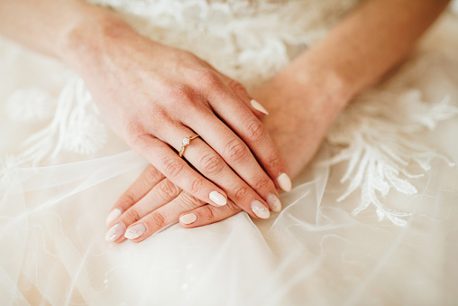 Bride's hands with an engagement ring on them.