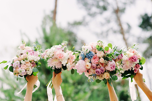 Bridesmaids holding wedding bouquets outdoor. Happy wedding concept.