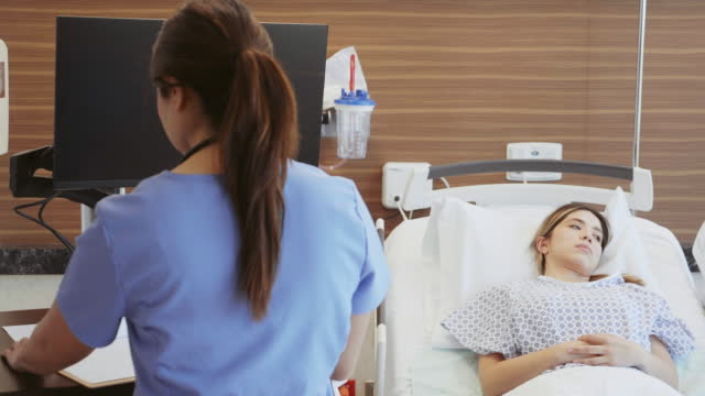Nurse uses computer in patient's hospital room
