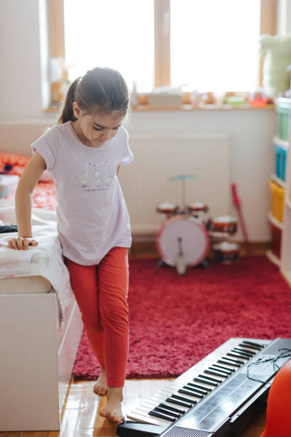 istock Little girl having fun while learning to play music instrument 1402892992
