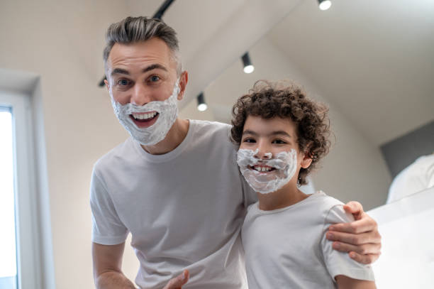 istock Dad and son looking funny with shaving foam on their faces 1402893211