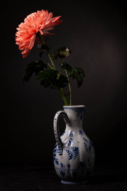 istock Bright red orange chrysanthemum in a classic Delft pottery jug. 1402894838