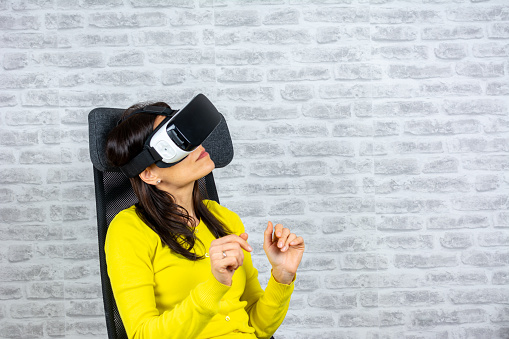 beautiful woman wearing a VR headset and experiencing a virtual reality simulation, metaverse and cyberspace concept. Woman with glasses of virtual reality. Future technology concept