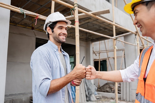 The engineer manager and foreman construction workers shake hands on the construction site