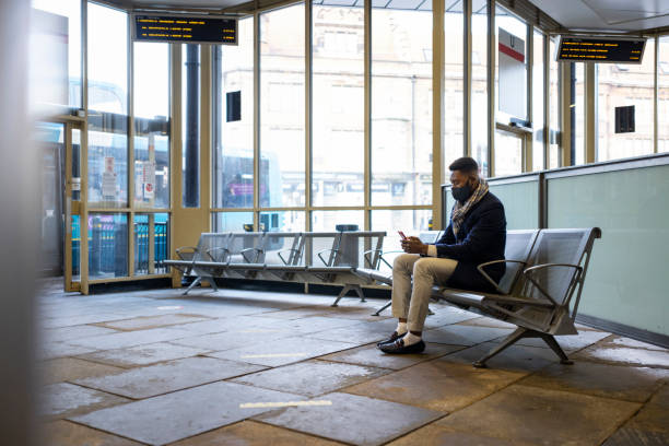 istock Man With Face Covering Using Phone in Bus Station 1402896388