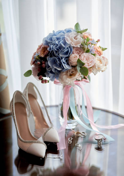 Bridal bouquet, bride shoes, wedding rings and earings on wood table, copy space. Luxury wedding accessories and jewelry. Wedding concept stock photo