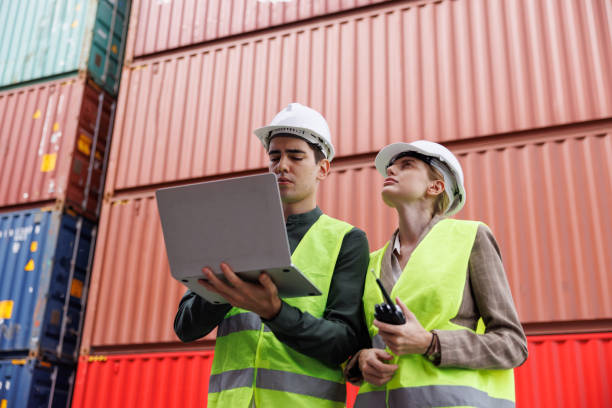 istock the man engineer using laptop in the import- export container shipping yard. the woman worker using walkies talkie concept : using technogy control logistic with big data analysis. 1402898040