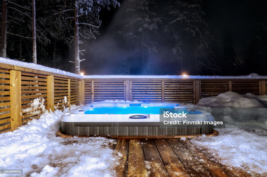 Hot tub at midnight The warm hot tub invites you to relax in the beautiful winter landscape under the stars. Hot Tub Stock Photo
