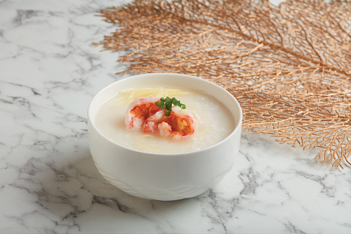 Crystal Prawn Congee served in a bowl isolated on wooden board side view dark background