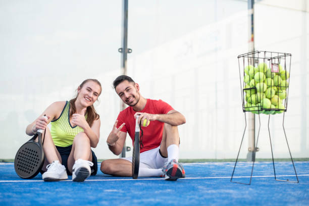 Happy couple looking at camera in paddle tennis class stock photo