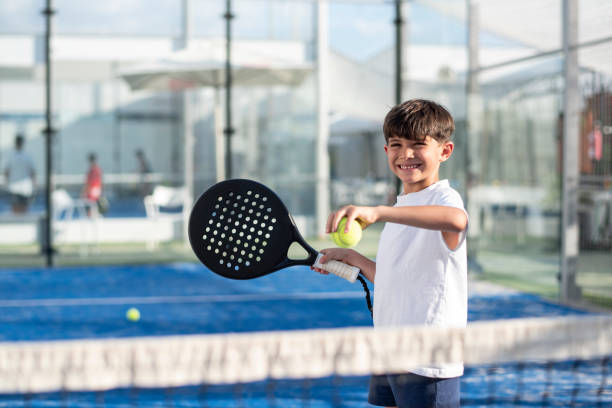 ragazzino che gioca a paddle tennis in campo, sorridente pronto per il servizio - padel foto e immagini stock