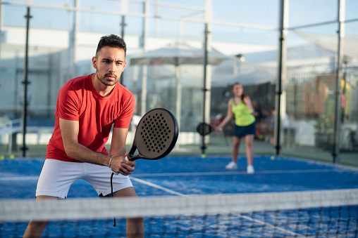 Couple playing paddle tennis in court