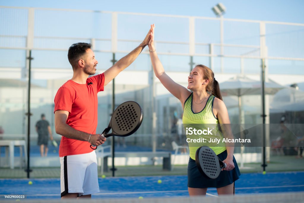 Couple playing paddle tennis in court, hi five fair play gesture Padel Stock Photo