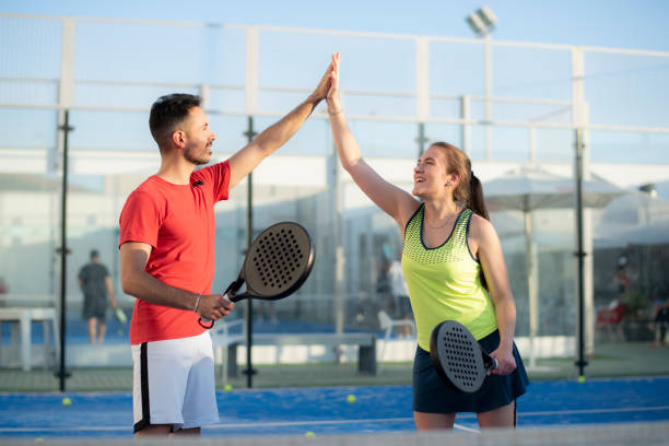 Couple playing paddle tennis in court, hi five fair play gesture stock photo