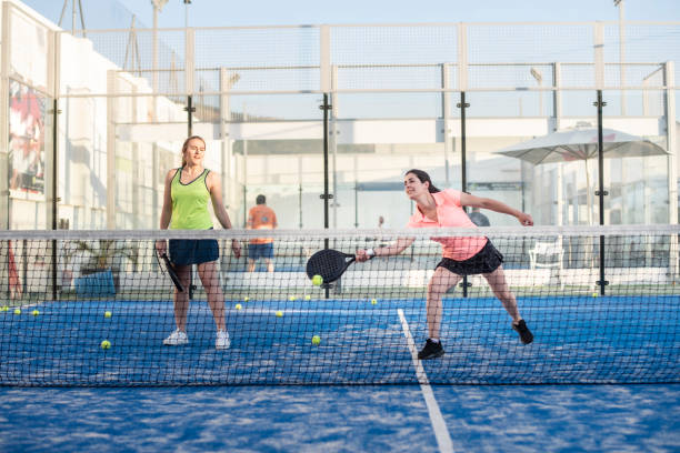two women playing paddle tennis in court, padel training stock photo
