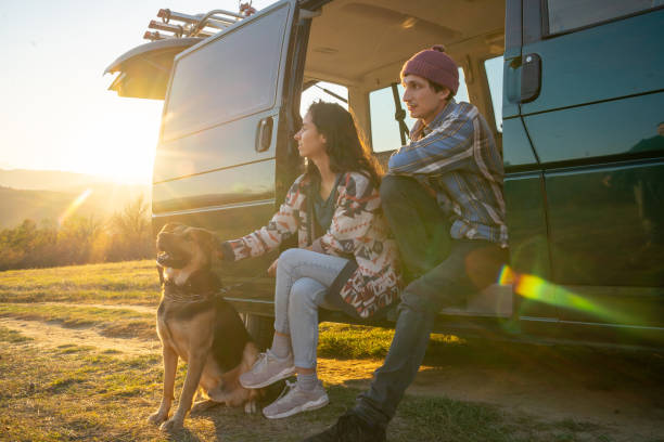 Sitting on the steps of a mini van to look at the view A boyfriend and girlfriend and their dog are sitting on the mini van steps and enjoying the country view with the sun setting behind them hipster car stock pictures, royalty-free photos & images