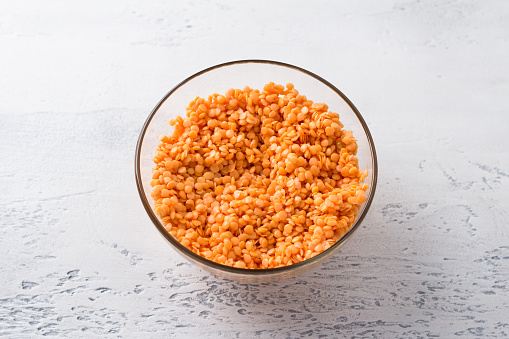 Raw soaked lentils in a white bowl on a light gray background, top view. Healthy Food Concept