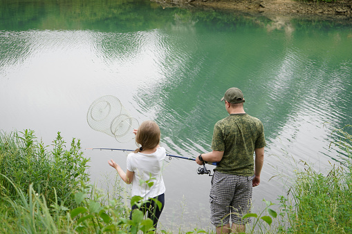 A son and mother on a fishing trip hold a largemouth bass.
