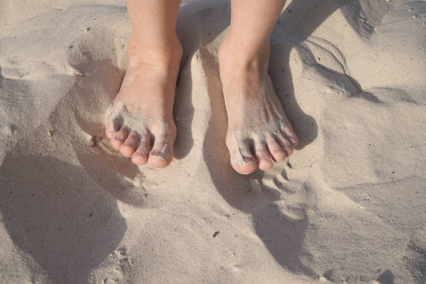 istock Two bare children's feet close-up on the sand 1402904501