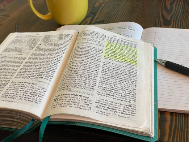 Open Bible laying on table with highlighted passage. II Corinthians 10 Bible laying open with teal colored book marks. Passage highlighted in yellow. Yellow coffee mug, notebook and pen in background hebrew script photos stock pictures, royalty-free photos & images