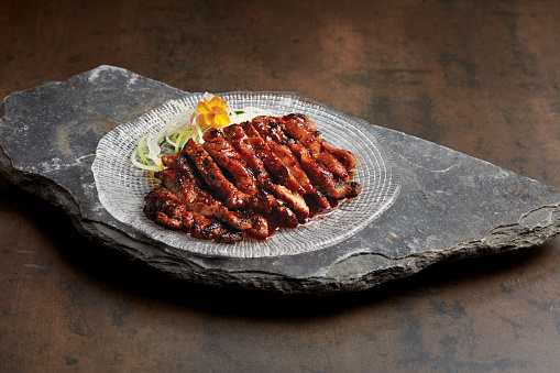 Char grilled Nagano Pork served in a dish side view on dark background