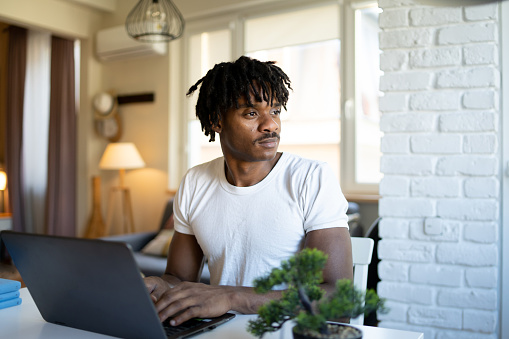 An African-American using his laptop on a table at home
