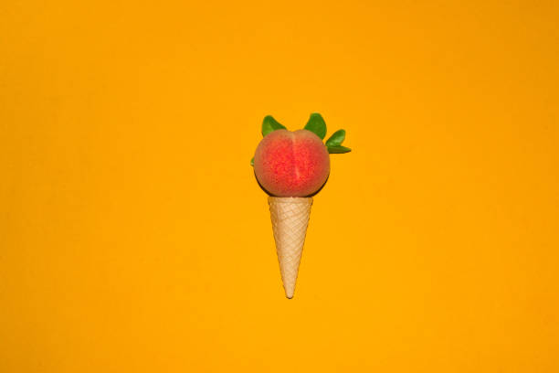 ice cream cone with peach ball on yellow background, creative summer healthy concept