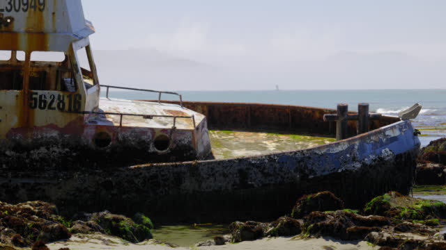 LOW ANGLE SHOT OF RUSTED FISHING VESSEL STUCK ON THE ROCKS.  4K, NO PEOPLE.