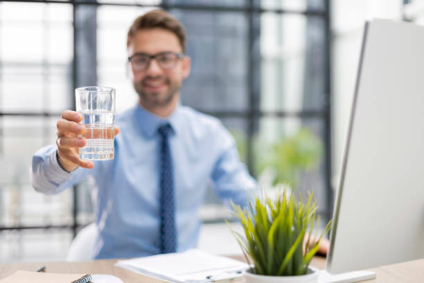 istock Handsome businessman using PC and drinking water in office area 1402909800