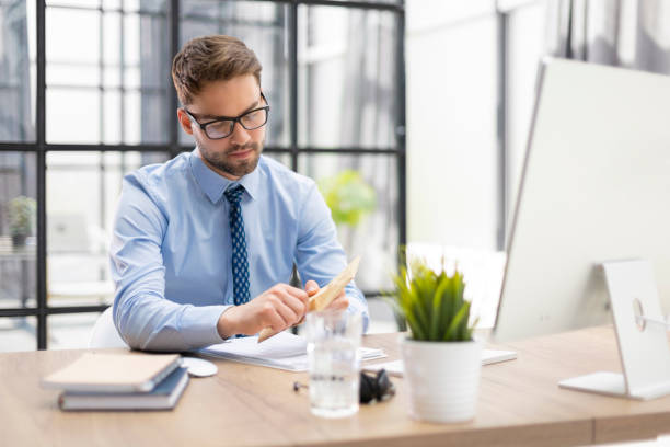 istock Handsome entrepreneur opening a padded envelope in a desktop at office 1402909852