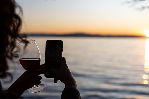 woman holding a cup and cellphone at sunset