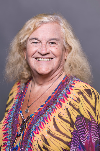 Portrait of an elderly transgender lady wearing a colorful dress.