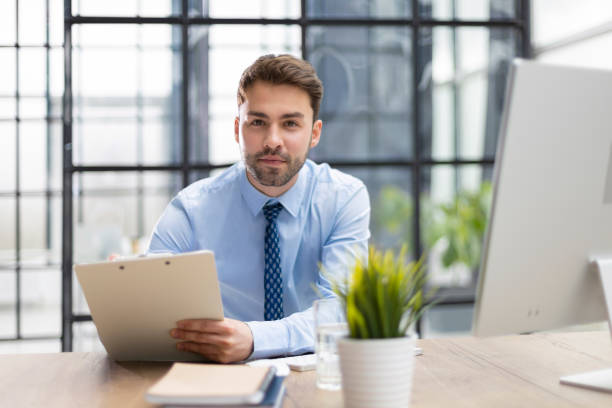 istock Young man is working with papers while sitting in the office. Successful entrepreneur is studying documents with attentive and concentrated look. 1402910558