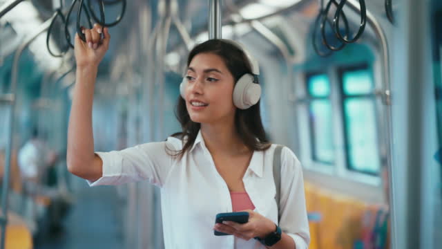 Woman holding handrail and listening music in the subway