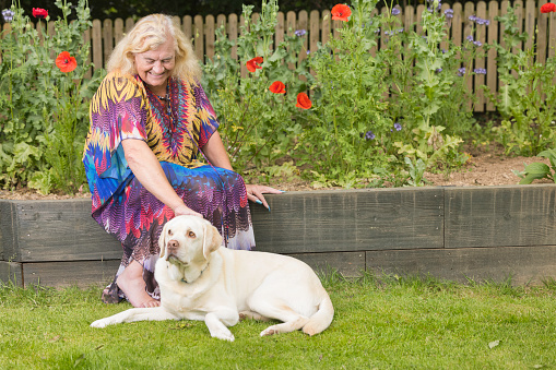 Elderly transgender lady in her garden with her rather sad dog.