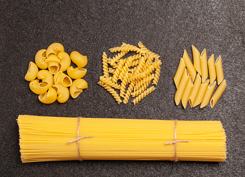 Spaghetti with variety of types and shapes of Italian pasta on black background. Top view.