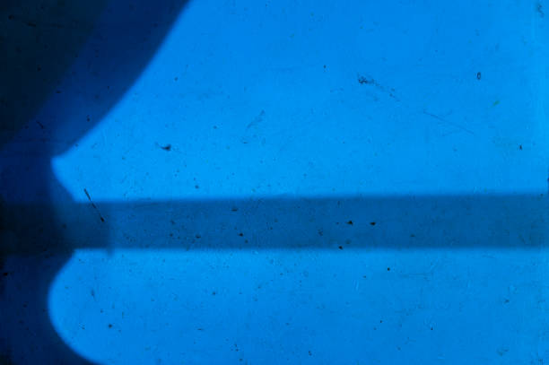 Night shadows on the blue wall. Abstract gray silhouette on a rough stained wall. Creative multitasking background to solve various design problems. Selective focus.
